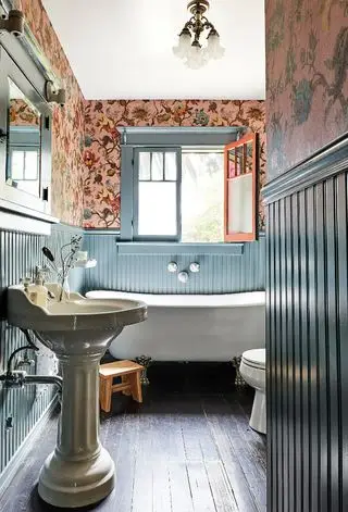 koupelna s modrým obložením a růžovou tapetou House of Hackney