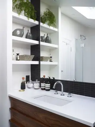 Weiße Badezimmerarbeitsplatte mit eingelassenem Waschbecken, Spiegel darüber und Regal an einer Seite
