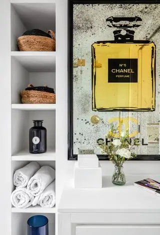Badezimmer mit großen Kunstwerken an der Wand und Regalen daneben
