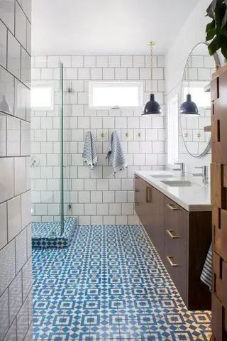 Cuarto de baño con baldosas estampadas estilo Cali azul, ducha y tocadores suspendidos.