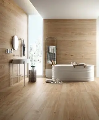 Baño con piso y paredes estilo madera porcelanato, bañera y tocador blancos.