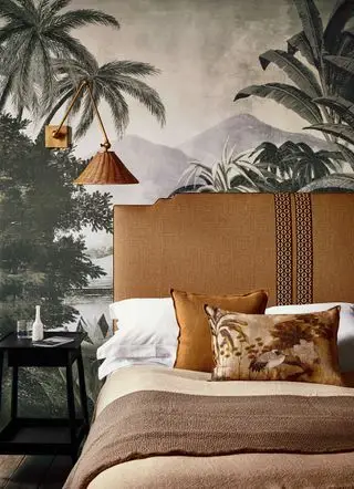 Um exemplo de ideias de cabeceira mostrando uma cama de estilo vintage com cabeceira laranja em frente a um mural de parede de selva