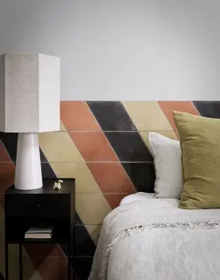 Um exemplo de ideias de cabeceira mostrando uma cabeceira de azulejos bege, laranja e preto