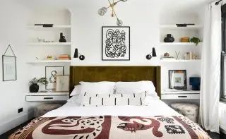 Dormitorio blanco con estantes a cada lado de la cama. Tocadores debajo