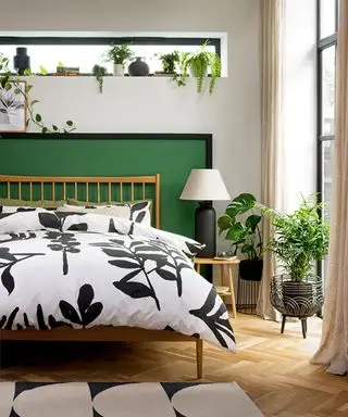 Dormitorio pintado con cabecera pintada de verde con estanterías y vegetación