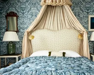 gran dormitorio con dosel y paredes de tela azul y blanca de ensemblier