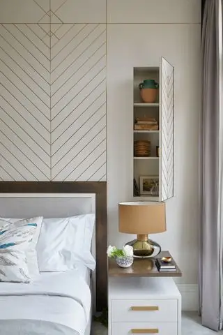 dormitorio neutro con almacenamiento oculto sobre la cama, cabecera moderna y detalles dorados en la pared