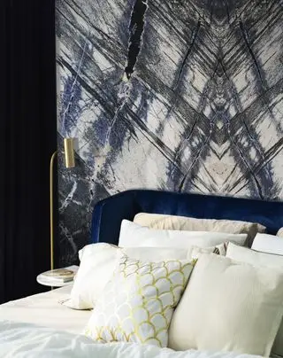 chambre bleue et blanche avec fond en marbre bleu, lit en velours bleu, literie blanche, lampe de table dorée