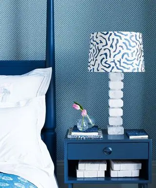 Chambre bleue et blanche avec papier peint à motifs et table d'appoint bleue