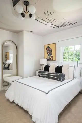 chambre moderne avec des couleurs neutres et des draps blancs avec du papier peint à motifs abstraits au plafond