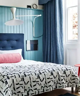 Chambre avec mur bleu, draps à motifs et applique murale
