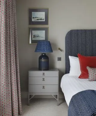 Ein Beispiel für Ideen für Schlafzimmervorhänge: ein blau-rot gemusterter Vorhang im marokkanischen Stil, ein blaues Bett und passende Kissen