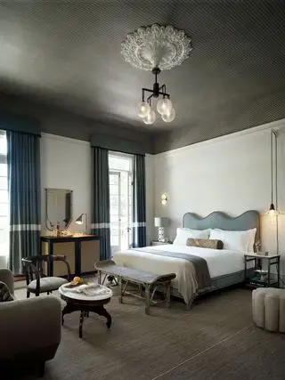 Schlafzimmer mit grau gemusterter Decke und graublauem Bettkopf