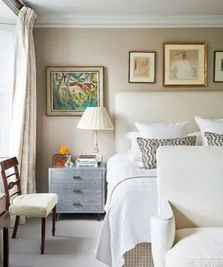 chambre neutre avec papier peint en toile de jute, commode de chevet argentée et œuvres d'art