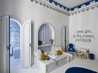 Dormitorio para niños azul y blanco con rayas azules y blancas, alfombra blanca, baño privado al fondo y bordes azules en la parte superior
