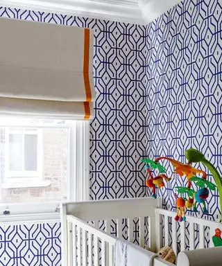 Una habitación infantil con paredes geométricas azules y blancas y una cuna blanca que ilustra a niños atemporales.