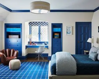 Un ejemplo de ideas de dormitorio para niños con una pared blanca, detalles pintados de azul y una silla con forma de guante de béisbol.