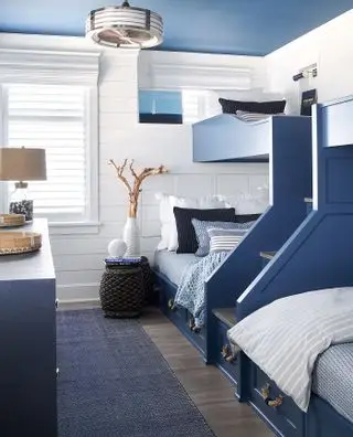 Literas azules con cajones y escaleras en un diseño azul y blanco inspirado en la costa que ilustra ideas de dormitorios para niños.