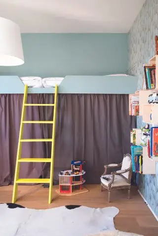 Dormitorio para niños con paredes y papel tapiz de color azul pálido, cortina marrón debajo de la cama alta, escalera amarilla y estantería