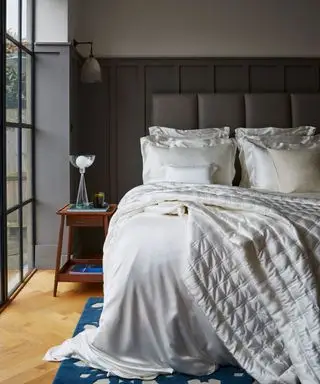 chambre grise avec literie en soie ivoire sur le lit