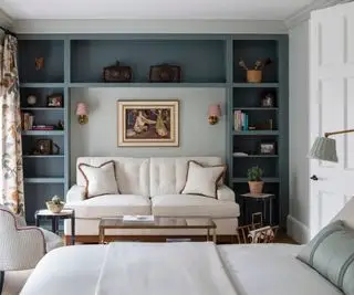 Un dormitorio grande con un sofá debajo de estanterías empotradas.