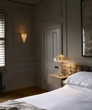 Un dormitorio neutro con lámparas decorativas de pared y de noche blancas.