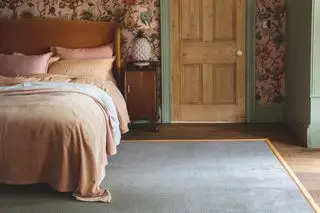 Schlafzimmer mit Blumentapete auf Holzboden und grauem Teppich