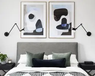 Schlafzimmer mit symmetrischem Doppelbettdesign, Kunstwerk über dem Bett, passenden schwarzen Wandleuchten, grauem Kopfteil, weißer und schwarzer Bettwäsche, grauen Kissen, schwarzen Beistelltischen aus Holz