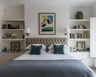 Hauptschlafzimmer mit Doppelbett und gepolstertem Kopfteil. Einbauregale und Fenster mit Fensterläden.