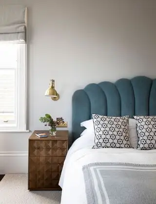 Graues Schlafzimmer mit grauem Muschelkopfteil und Wandlampe