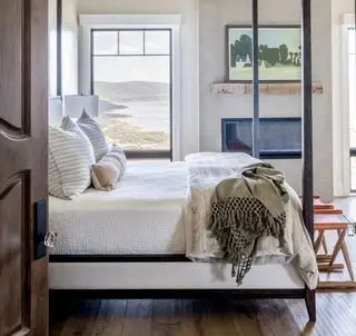 Ein Schlafzimmer mit Blick auf die Küste, Hartholzboden, einem Kamin und Kunstwerken