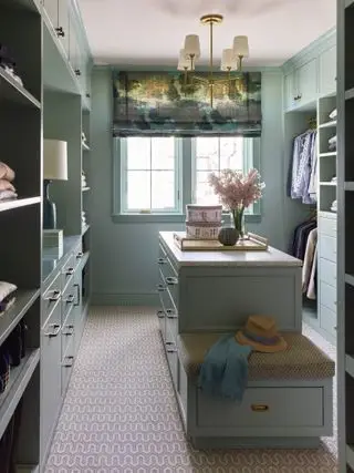 walk in closet malet i aquablå, persienner, midterø med skuffer, åbne og lukkede opbevaringssektioner, lille bænk, mønstret tæppe, pendel