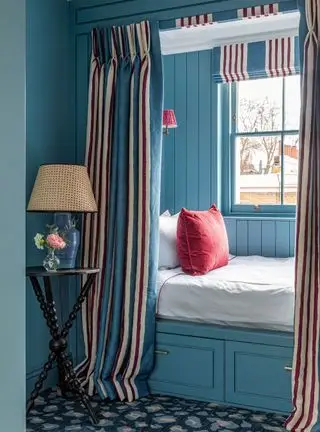 Camera da letto blu con angolo accogliente e tende a righe