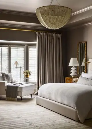 camera da letto dai colori tortora e letto matrimoniale con poltrona chaise
