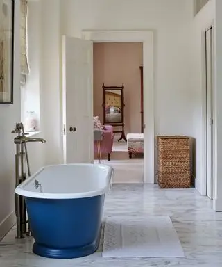 Un esempio di idee per la camera degli ospiti che mostra un bagno in marmo con una vasca autoportante blu