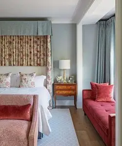 Come decorare una camera degli ospiti illustrata da un letto a baldacchino rosso e bianco con pareti e tende blu.