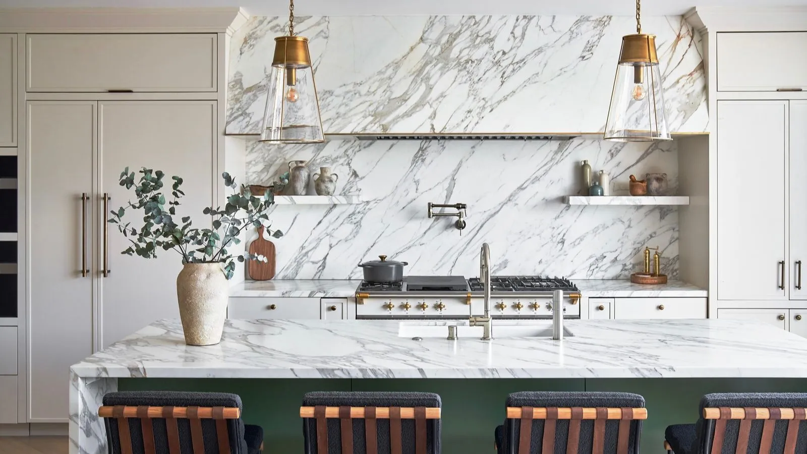 Et stort kjøkken med hvite skap marmor benkeplate og backsplash og en grønn øy' loading='lazy' title=