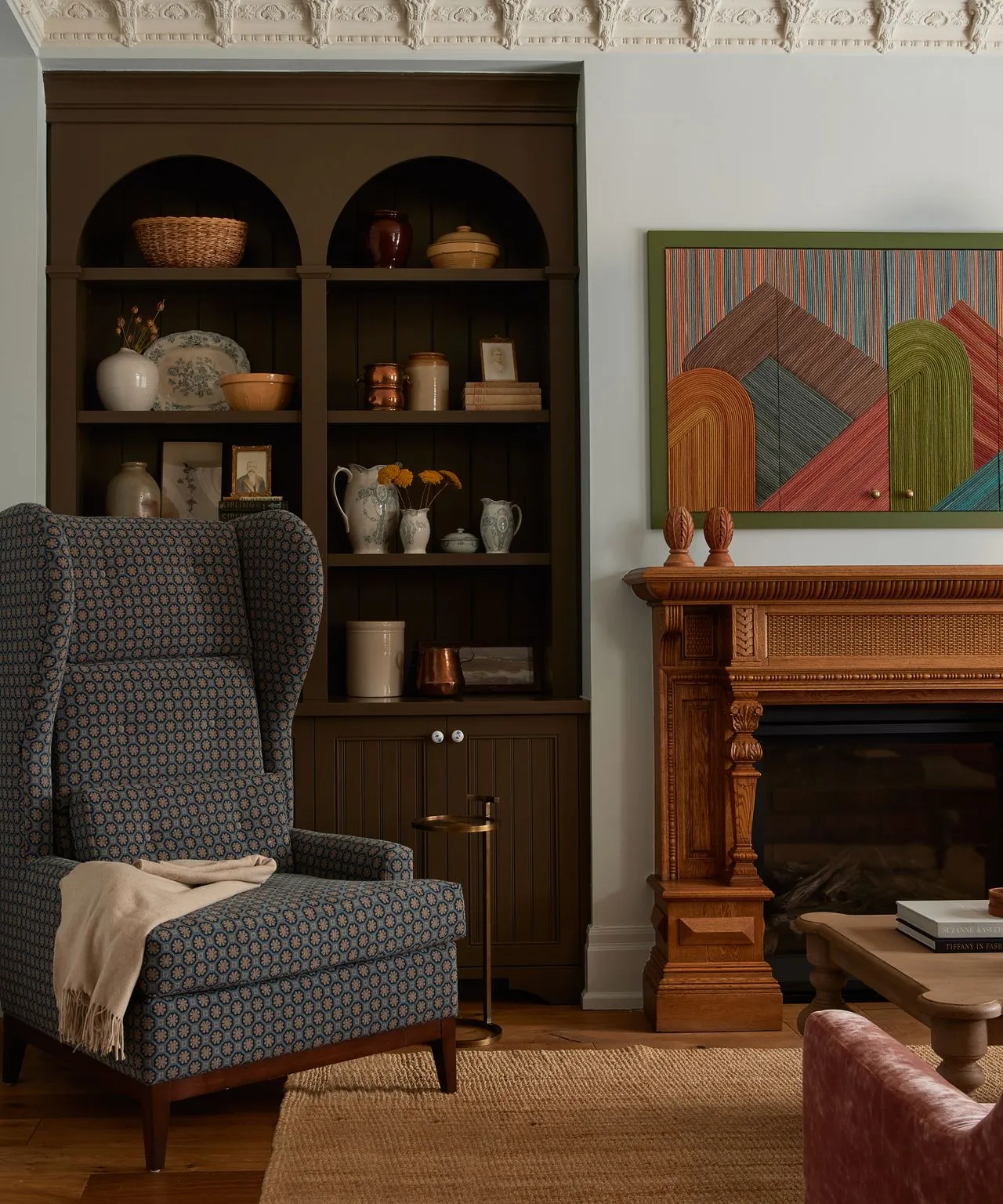 Salón con gran sillón gris y estantería llena de antigüedades.' loading='lazy' title=