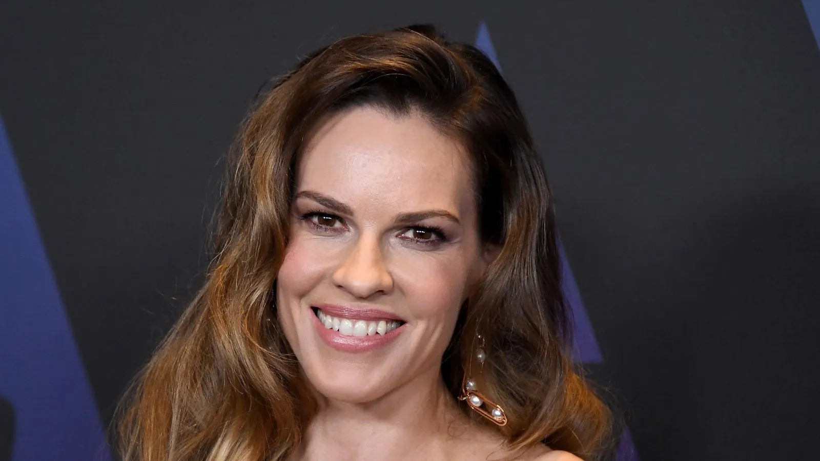 Hilary Swank em um fundo preto e azul' loading='lazy' title=