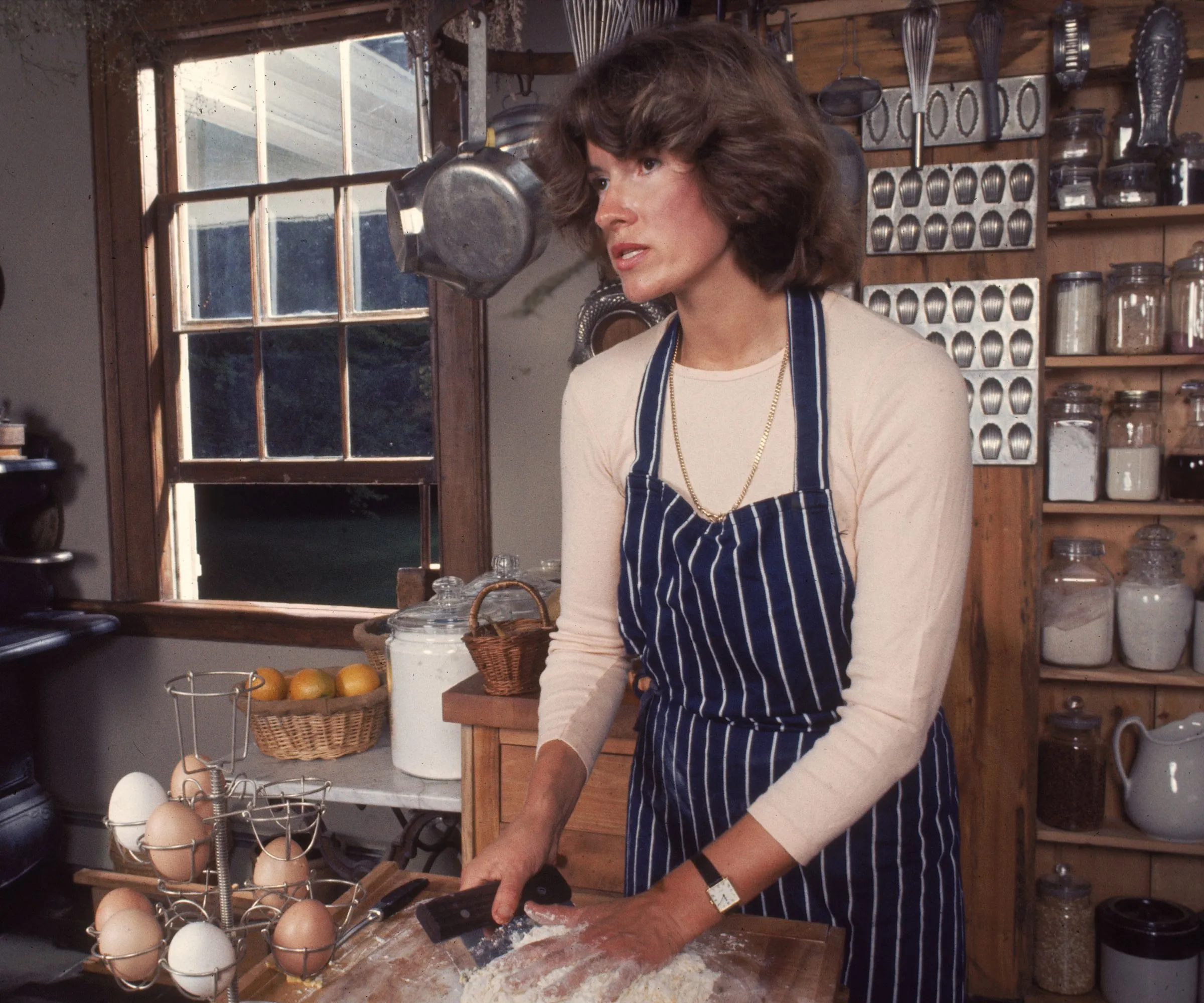 Martha Stewart på gårdskjøkkenet sitt med oppbevaringskrukker bak seg og puddingformer' loading='lazy' title=