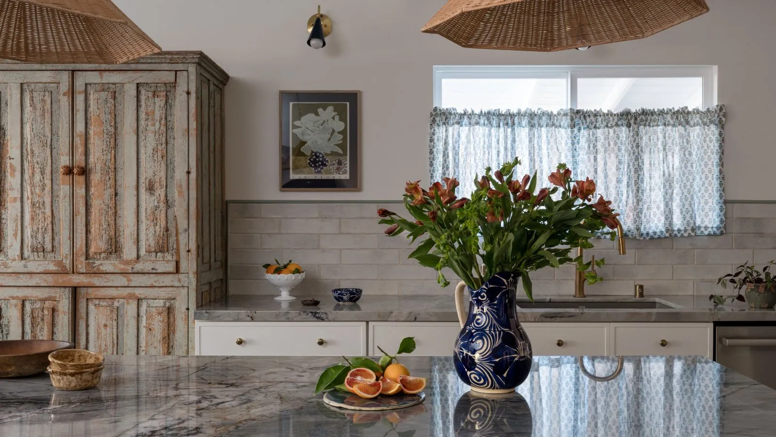 rustikk vintage-inspirert kjøkkendesign min Gilded Hearth med en benkeplate i blå marmor og et vindu kledd med en blå blomsterkafégardin' loading='lazy' title=