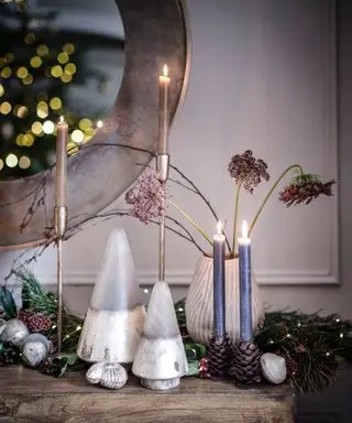 Wann sollte man mit der Weihnachtsdekoration beginnen? Nahaufnahme eines dekorierten Kaminsimses, Vasen mit Blumen und Weihnachtsschmuck