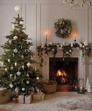 Wann sollte man mit der Weihnachtsdekoration beginnen? Geschmückter Weihnachtsbaum im Wohnzimmer neben dem Kamin