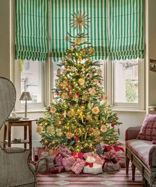 わら飾り、赤いつまらないもの、金色のライトが付いたクリスマス ツリー