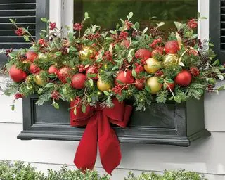Weihnachtsdeko-Ideen für Fenster mit einer Fensterbox, gefüllt mit roten und goldenen Kugeln und einem roten Band