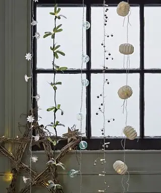 Weihnachtsdeko-Ideen für Fenster mit zahlreichen verschiedenen Stilen von Lichterketten, die vertikal von der Oberseite des Fensters hängen
