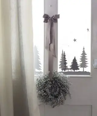 Ideen für weihnachtliche Fensterdekoration mit grau-weißen Baum- und Schneeflockenaufklebern in der Fensterscheibe einer weißen Tür