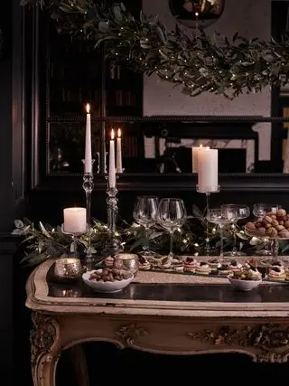 Mesa consola con comida festiva, guirnalda de mesa festiva y guirnalda colgante arriba
