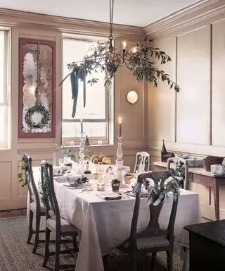 Comedor decorado con adornos navideños, guirnalda suspendida sobre la mesa del comedor