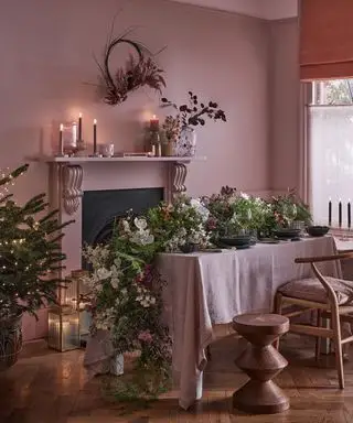 Comedor rosa con guirnalda de mesa grande y adornos navideños.
